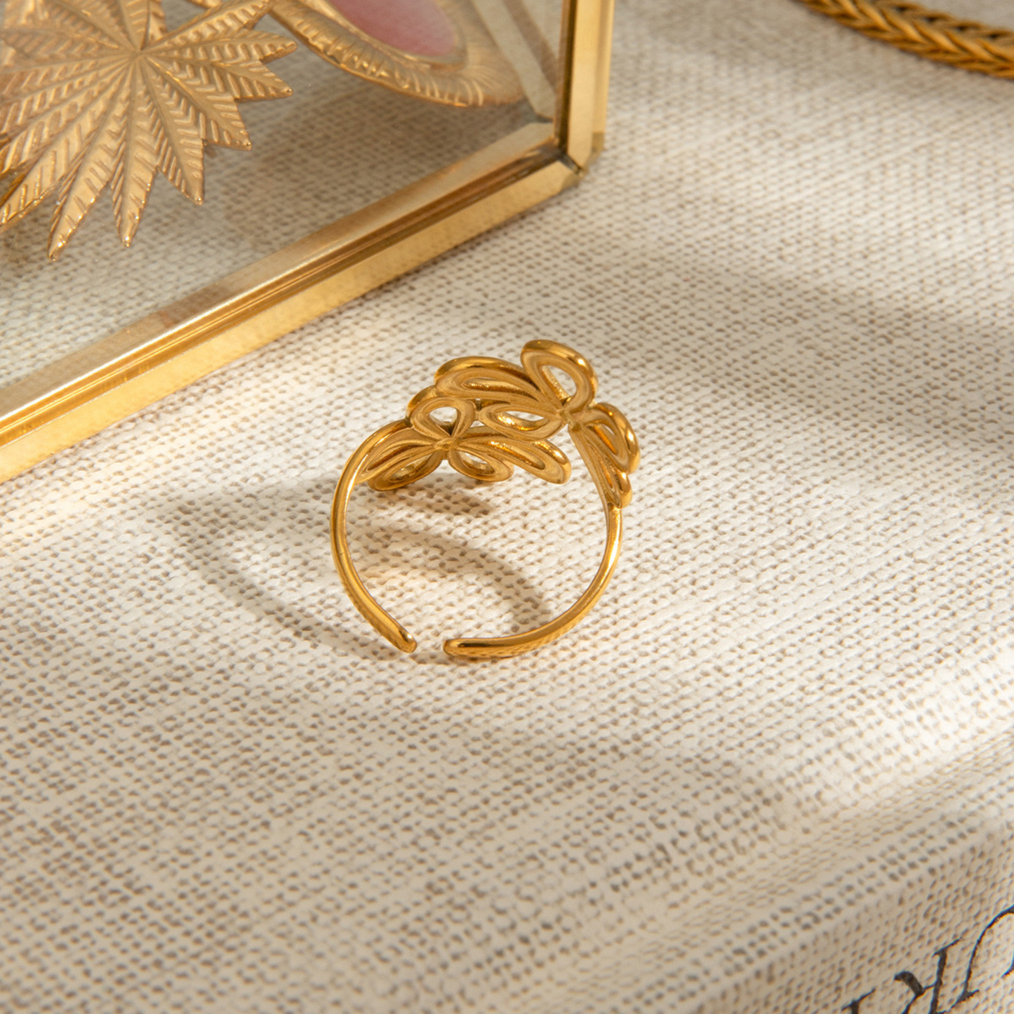Gold leaf-shaped ring on a textured beige surface