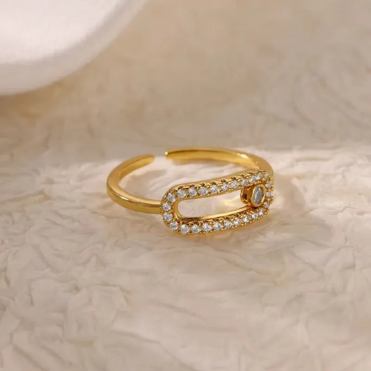 Gold ring with diamond accents on a textured beige surface