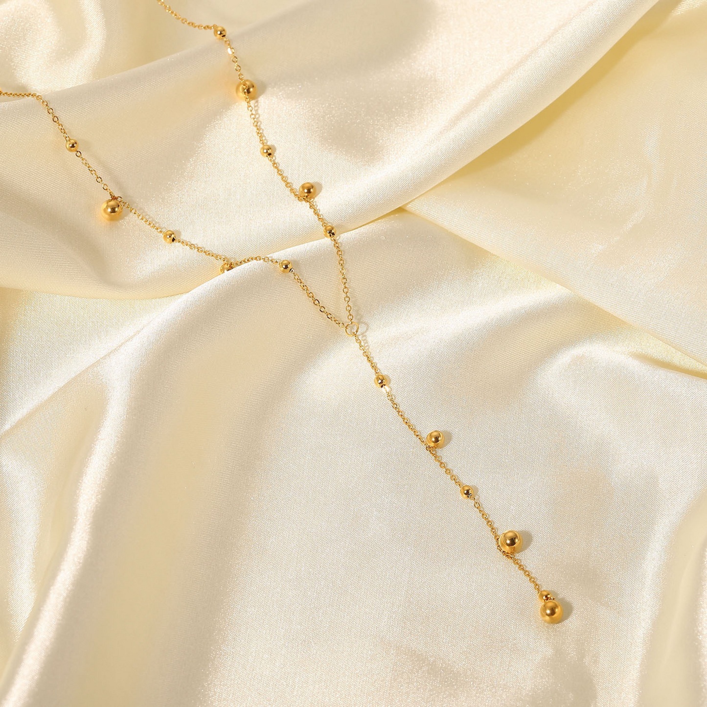 Gold necklace with small beads on a beige fabric background