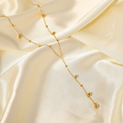 Gold necklace with small beads on a beige fabric background