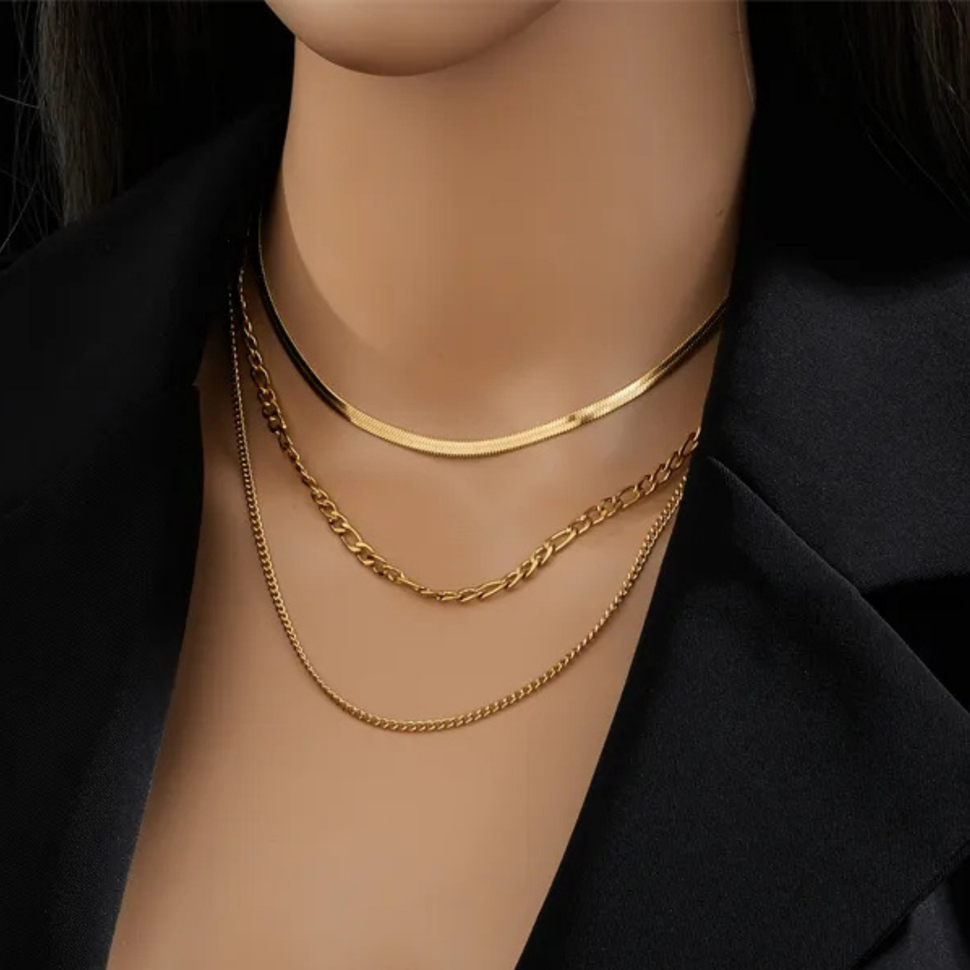 Gold necklaces on a mannequin with a black background