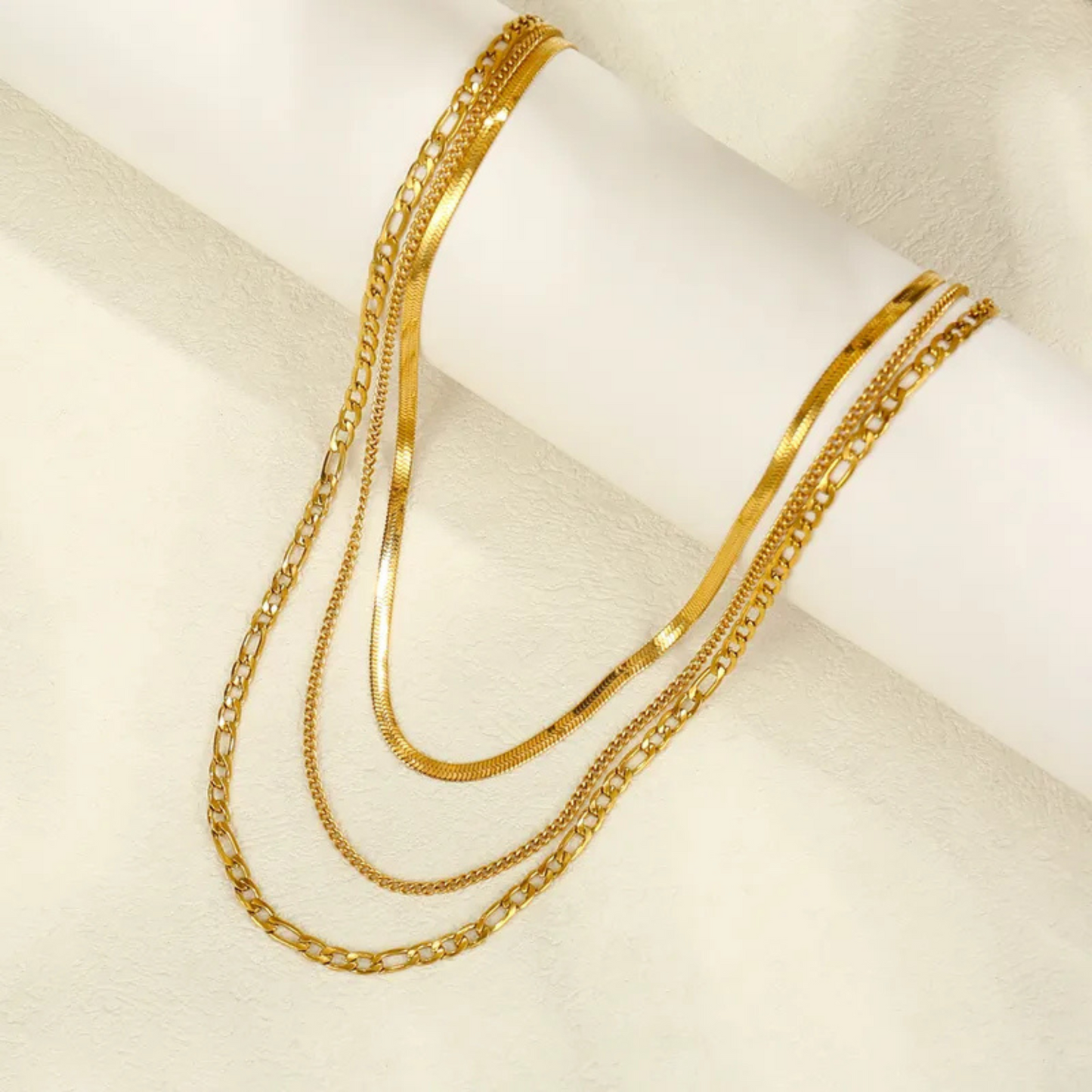 Gold chain necklaces on a white surface