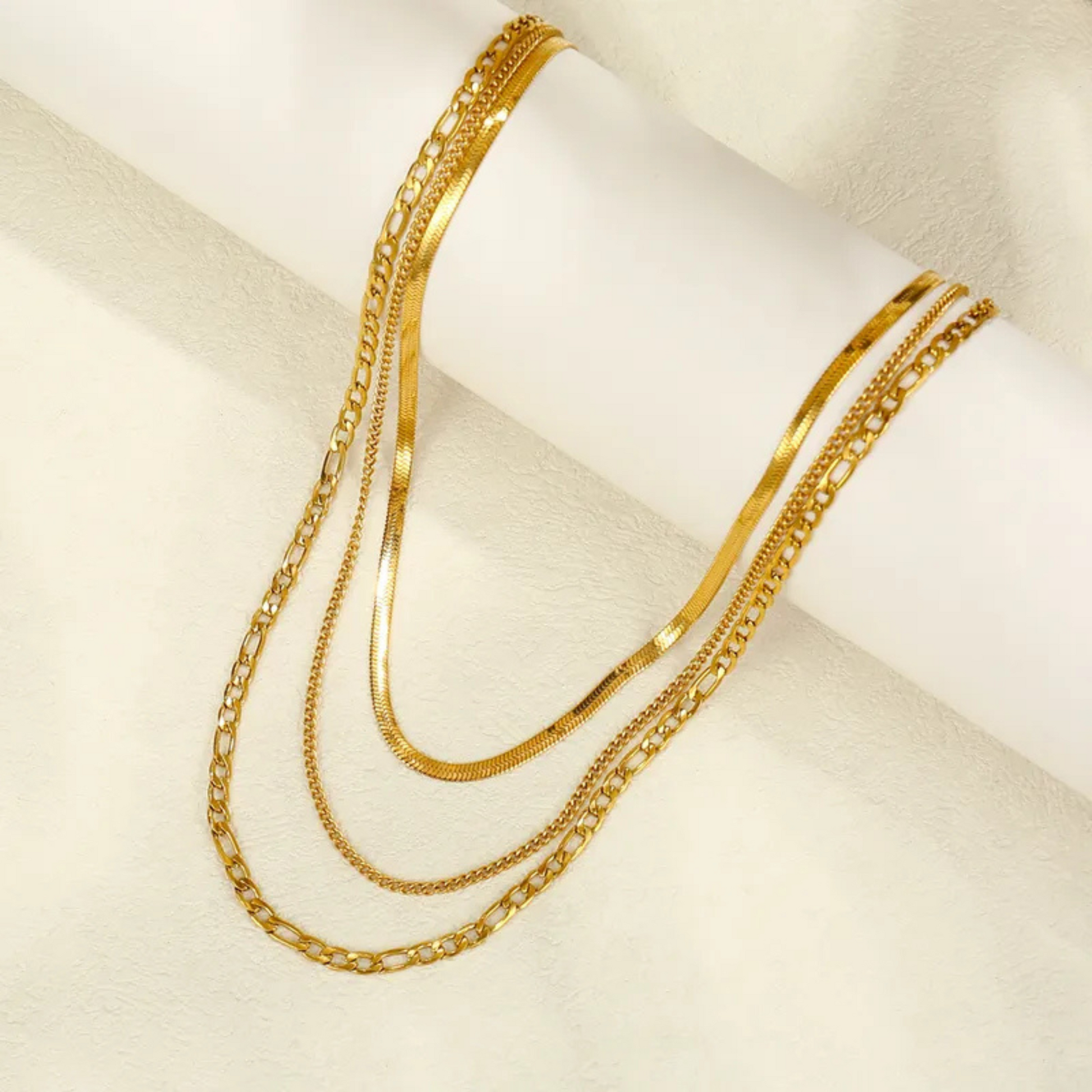 Gold chain necklaces on a white surface
