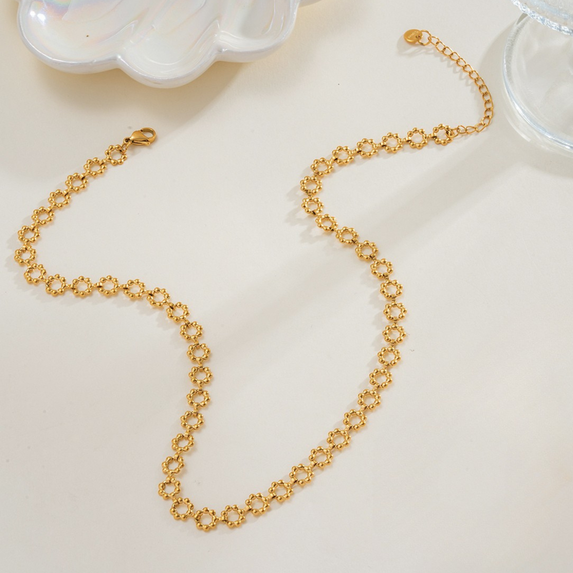 Gold chain necklace on a light beige surface