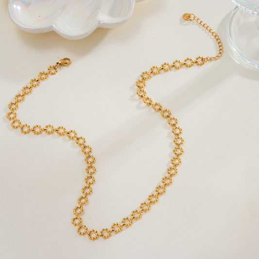 Gold chain necklace on a light beige surface