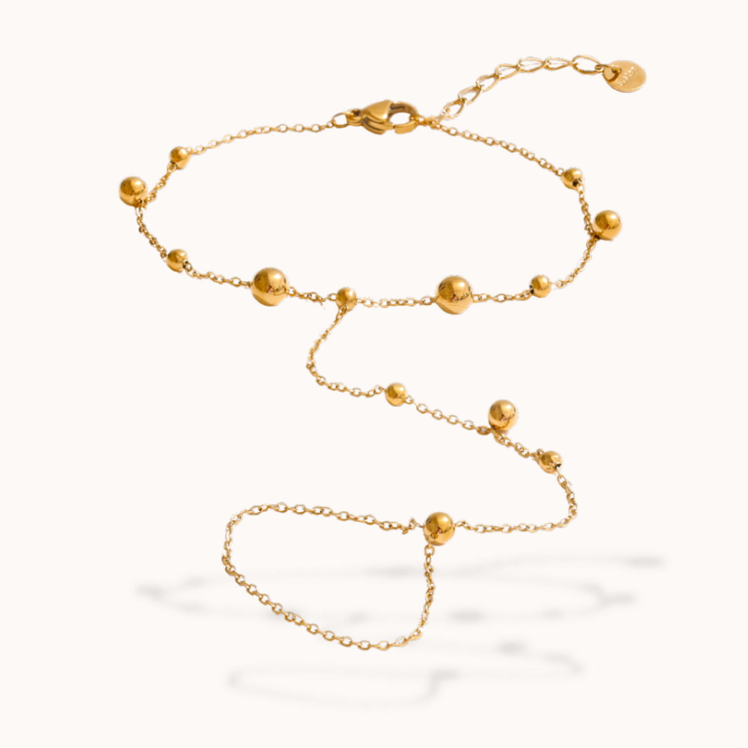 Gold ring bracelet with spherical beads on a white background