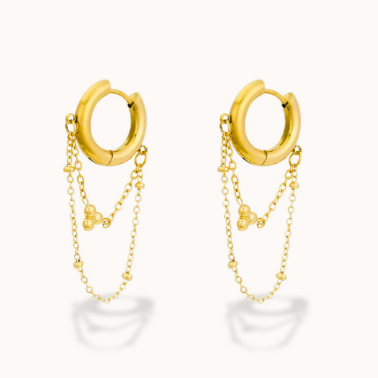 Gold hoop earrings with chains on a white background