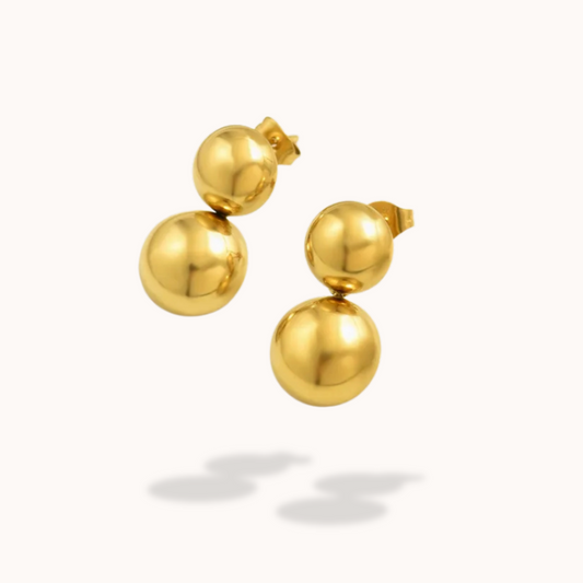 Gold ball earrings on a white background