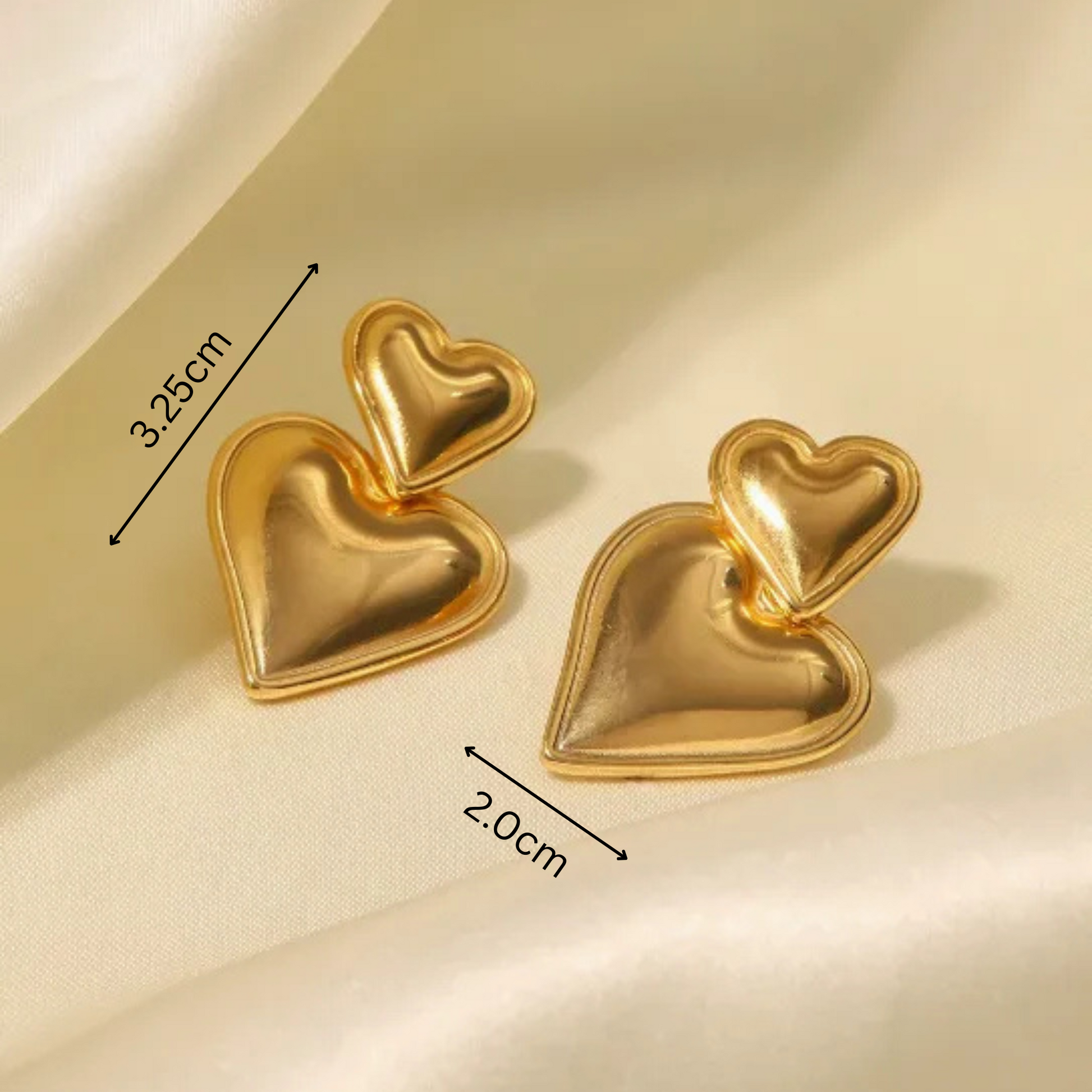 Gold heart-shaped earrings with measurements on a beige background