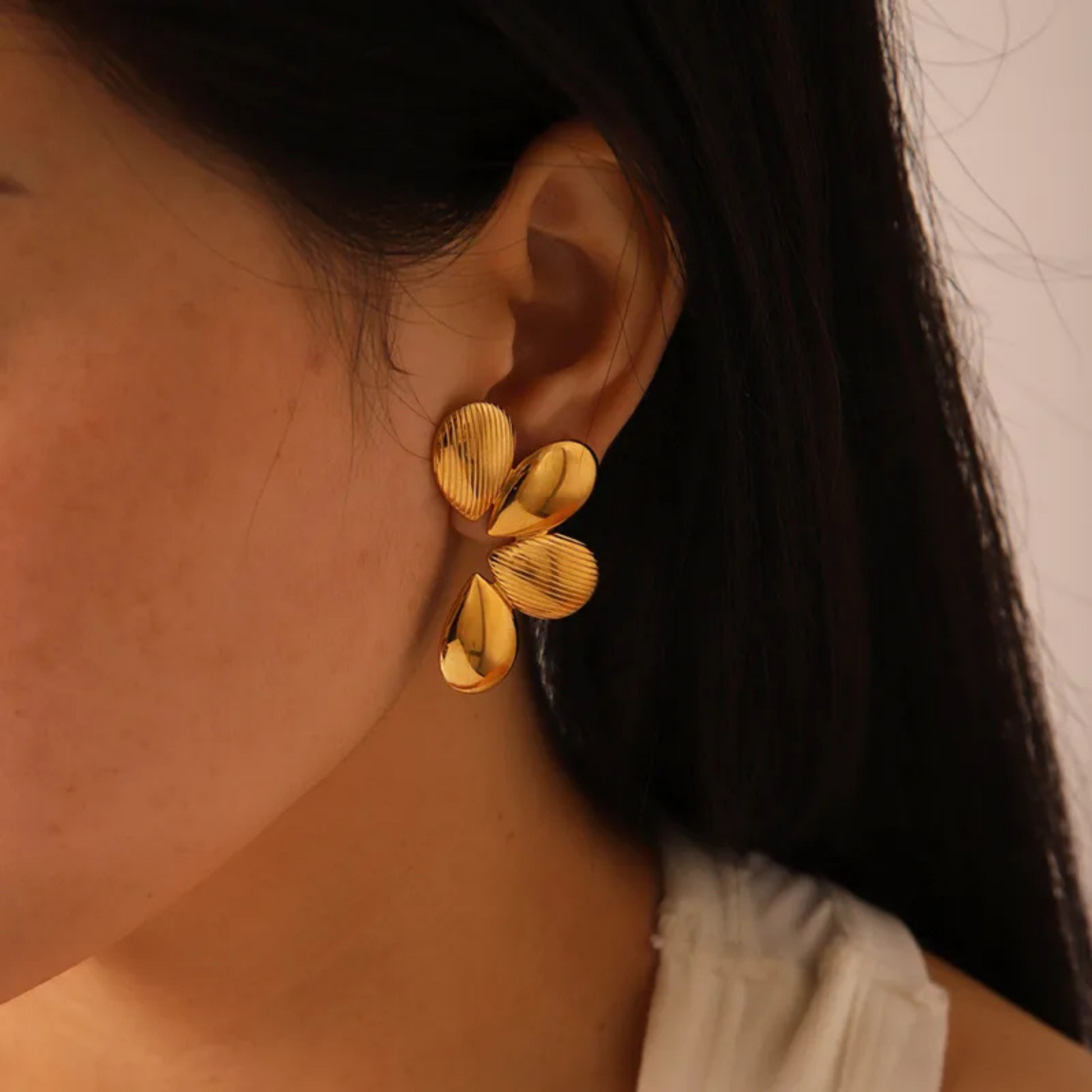 Close-up of a person wearing gold flower-shaped earrings.