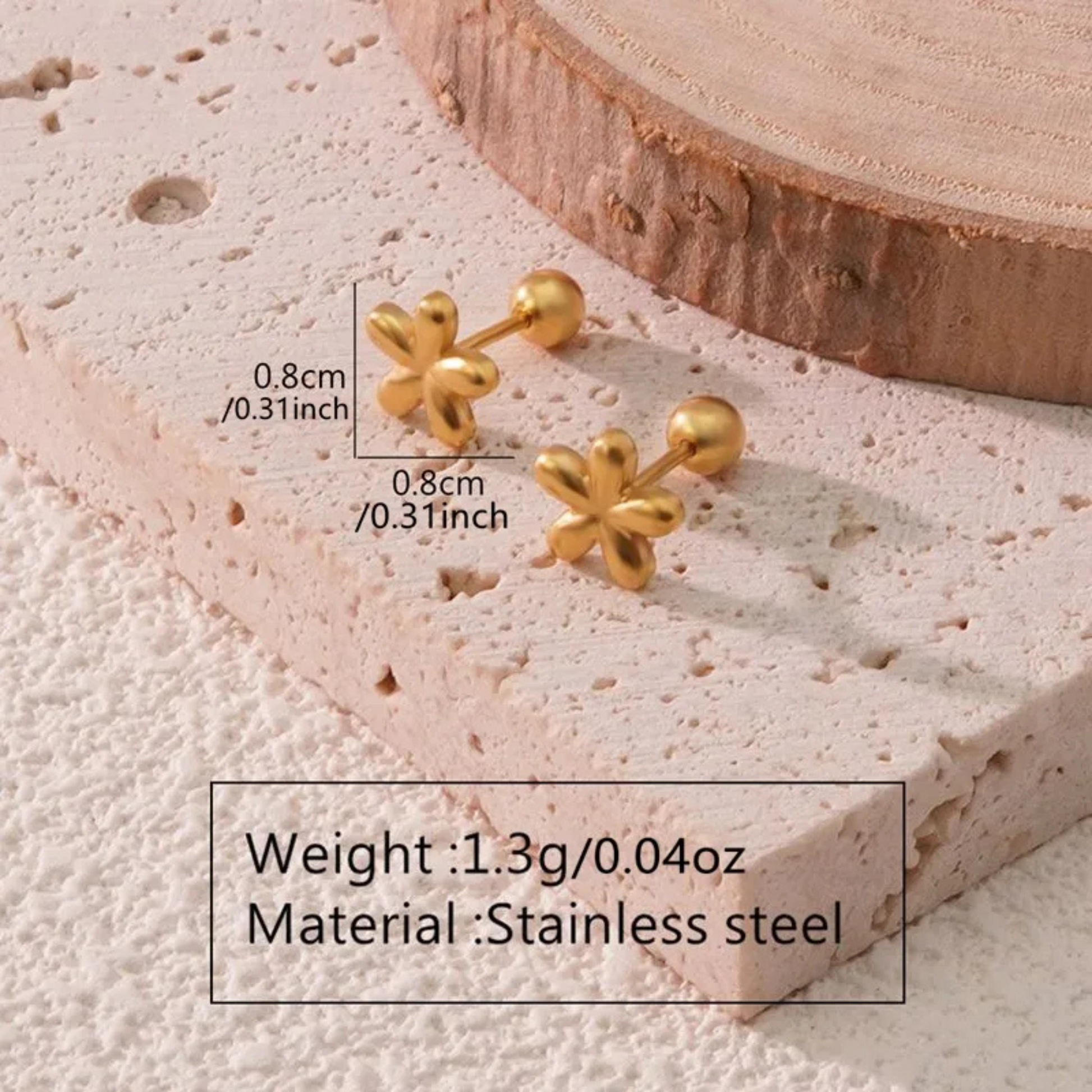 Gold flower-shaped earrings on a textured surface with measurements and material information.