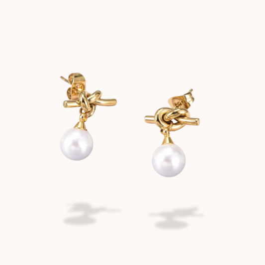 Gold earrings with pearl drops on a white background