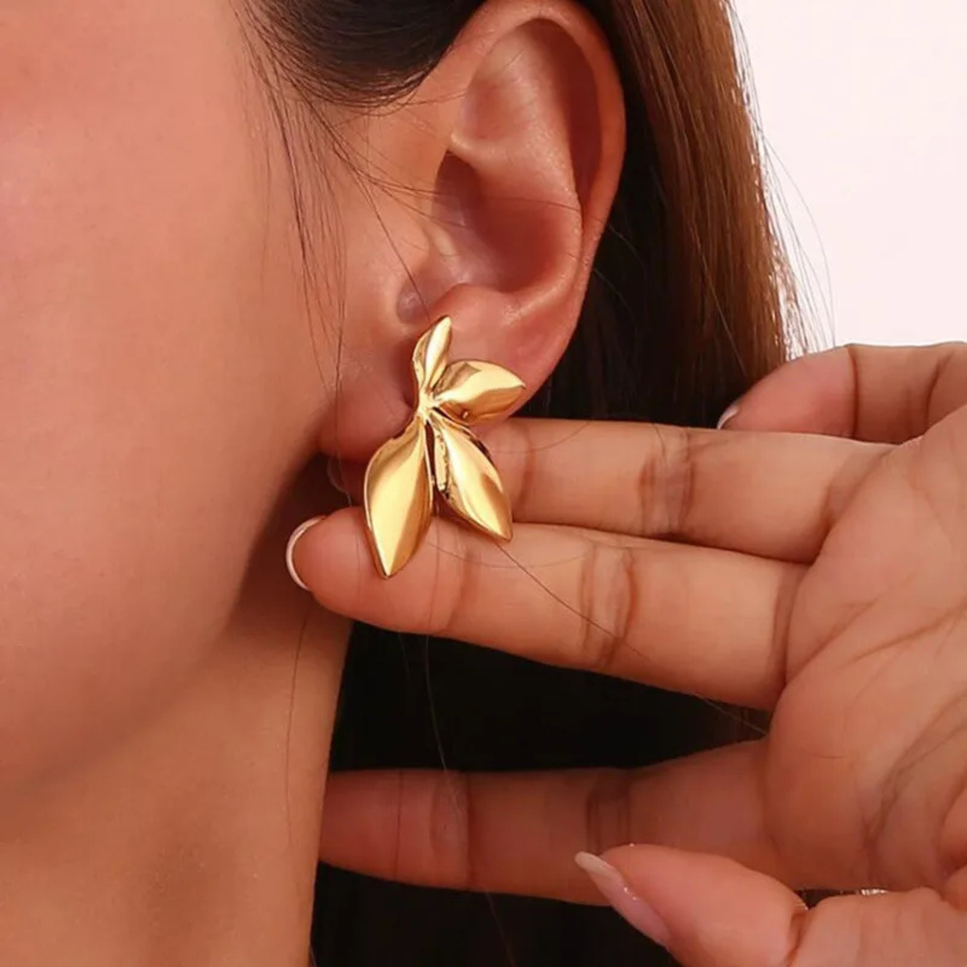 Gold leaf-shaped earrings on a model