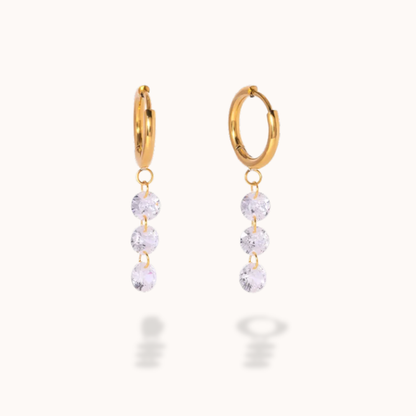 Gold hoop earrings with clear gemstones on a white background