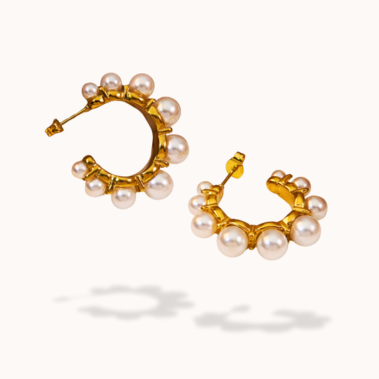 Gold hoop earrings with pearl accents on a white background