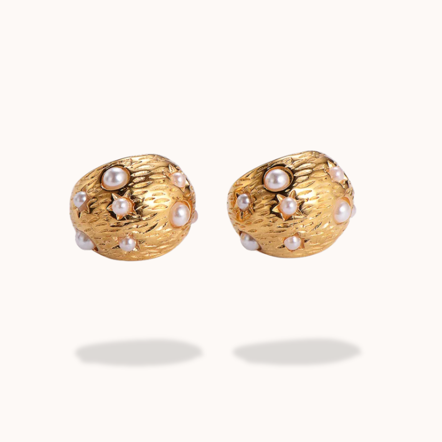 Pair of gold earrings with pearl-like stones on a white background