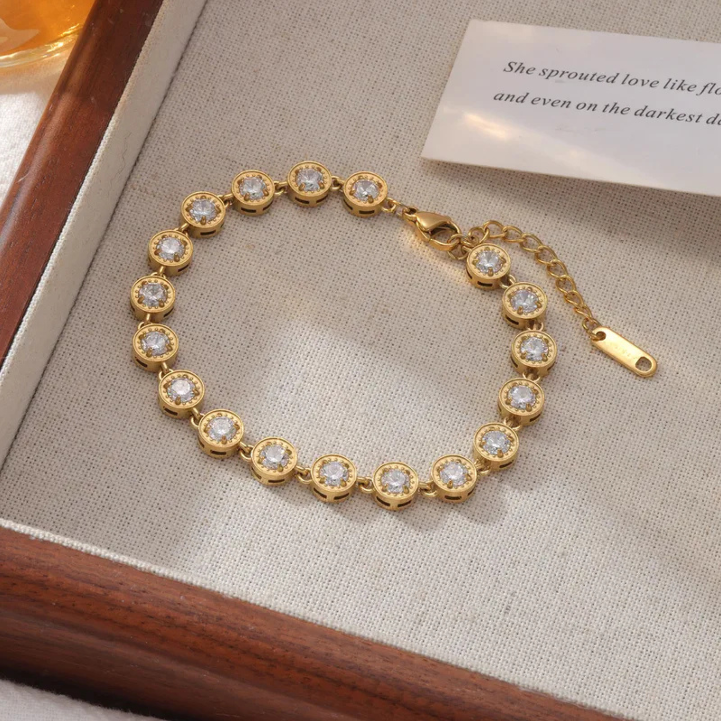 Gold bracelet with clear stones on a textured surface