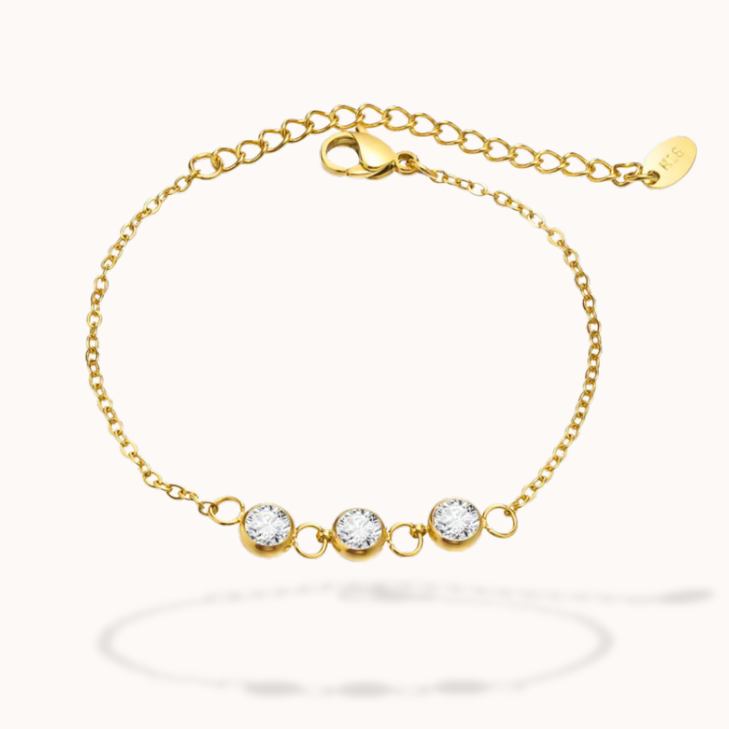 Gold bracelet with three clear gemstones on a white background