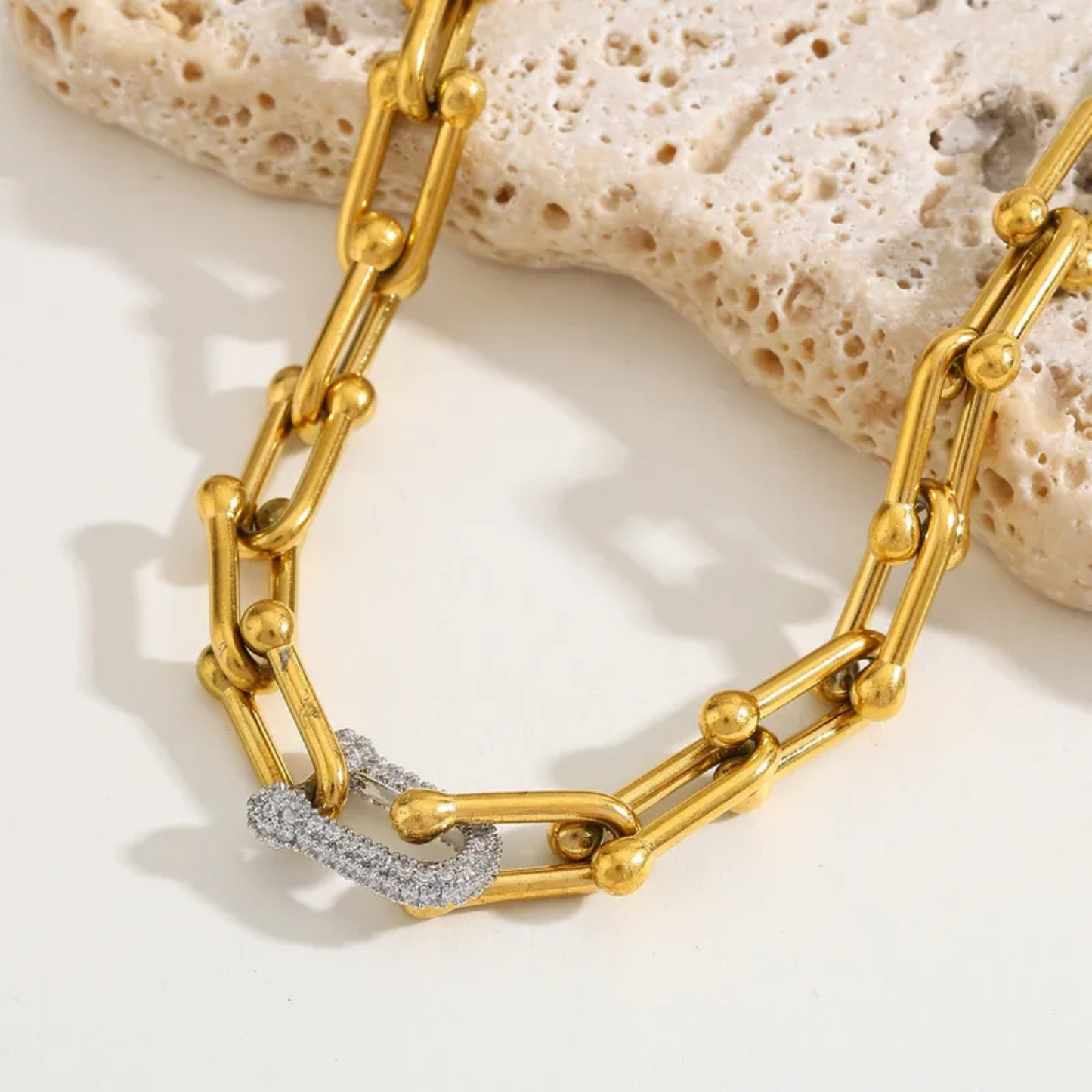 Gold chain bracelet with diamond accents on a textured surface