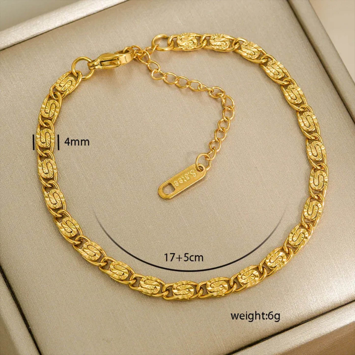Gold bracelet with measurements on a beige background
