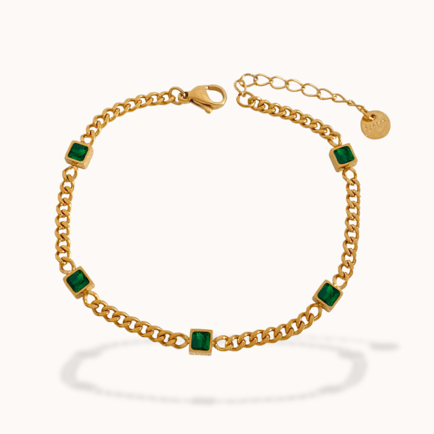 Gold bracelet with green gemstones on a white background