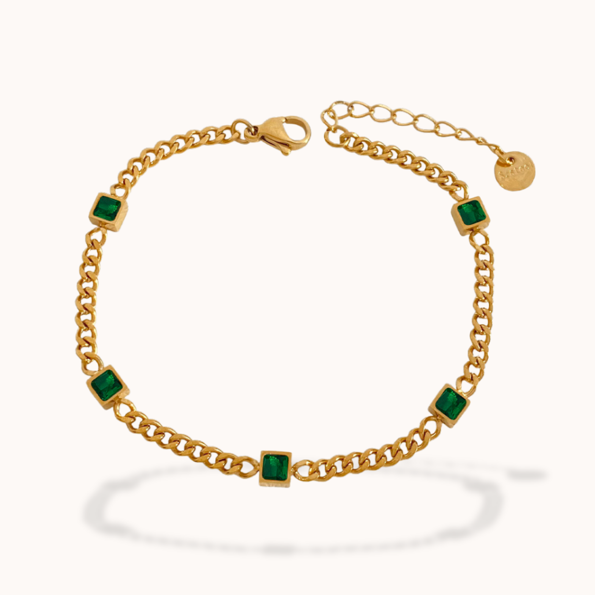 Gold bracelet with green gemstones on a white background