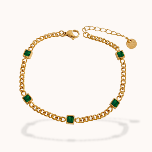 Gold bracelet with green gemstones on a white background