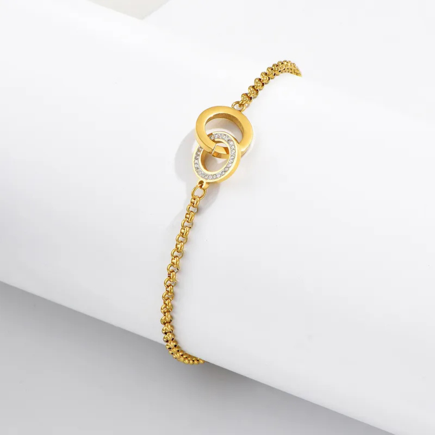 Gold bracelet with interlocking rings on a white surface