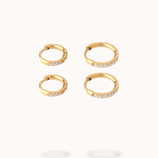 Set of gold hoop earrings with embedded stones on a white background