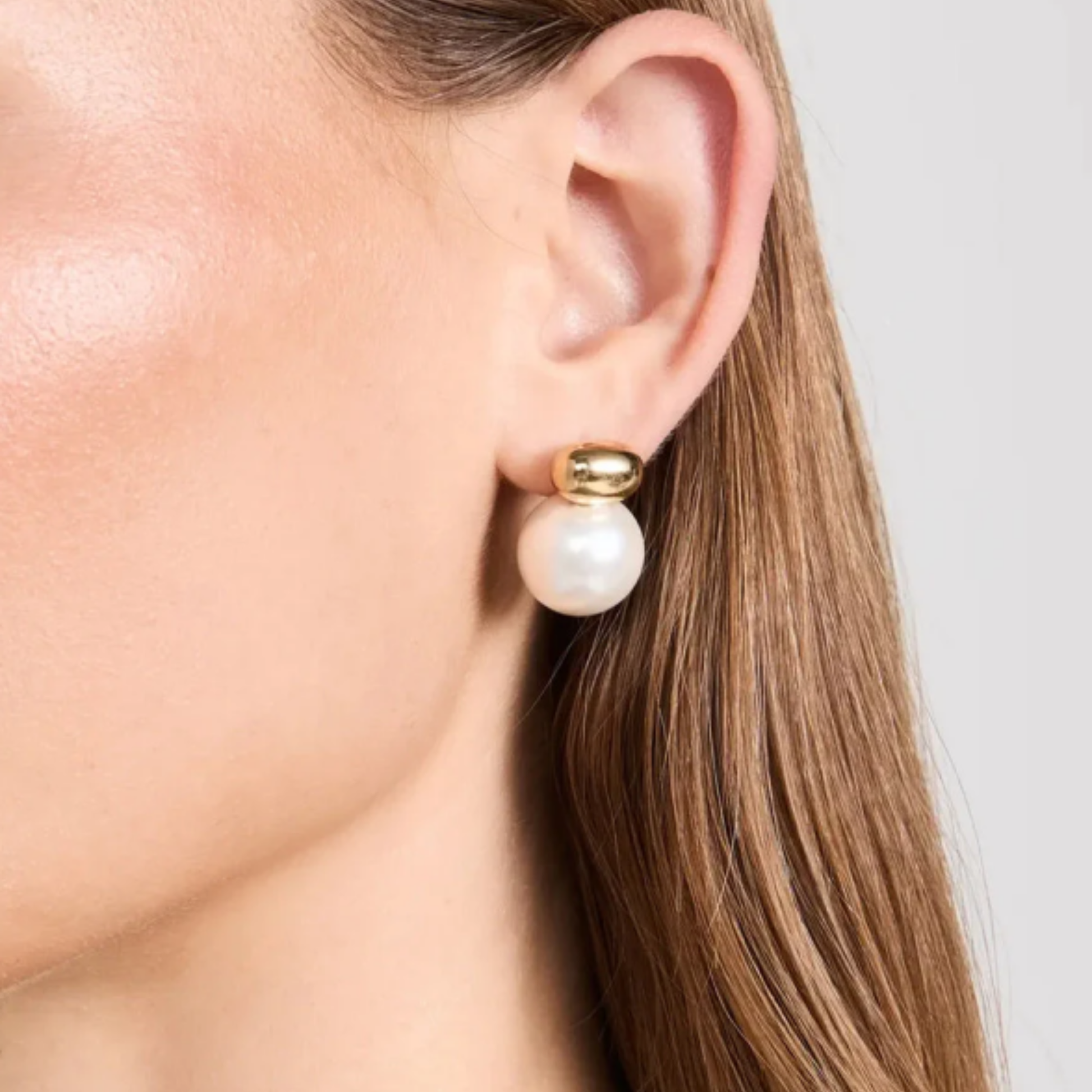 Pearl earring worn by a person with a neutral background