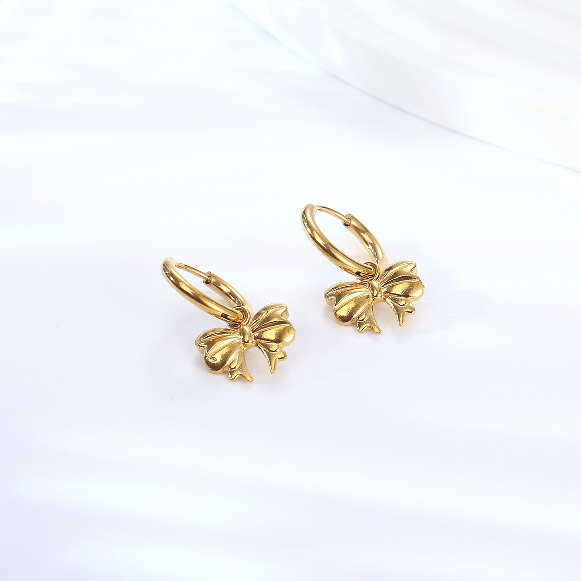 Gold bow-shaped earrings on a white background