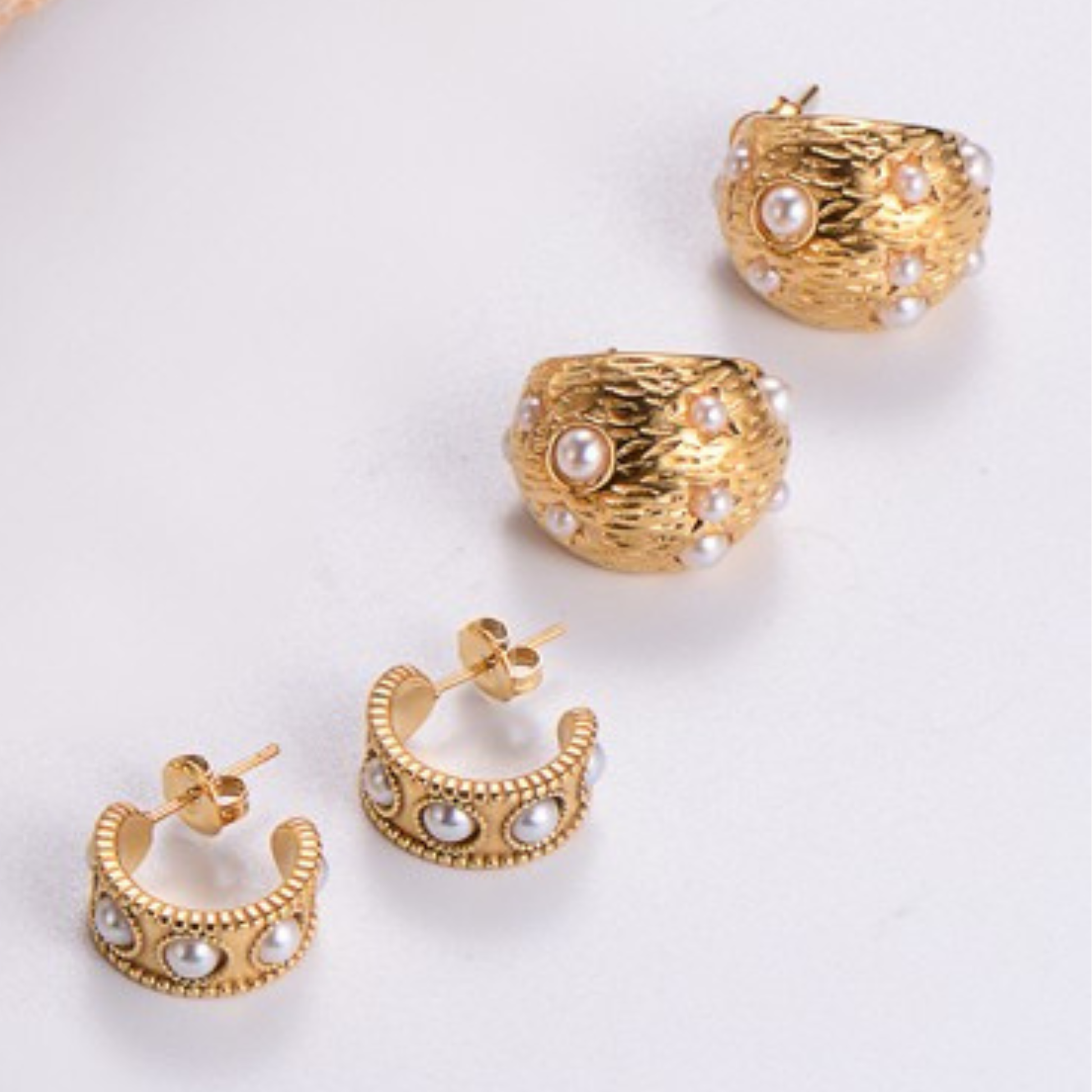 Gold hoop earrings with pearl accents on a white background