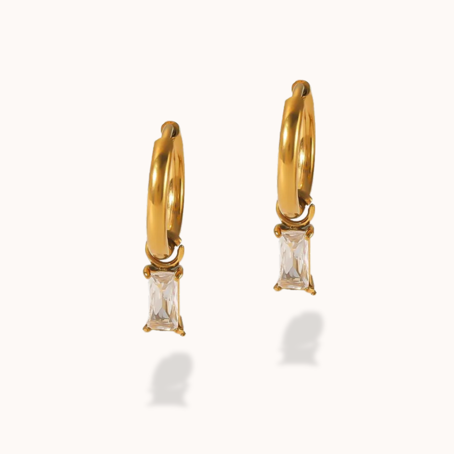Gold hoop earrings with clear gemstones on a white background