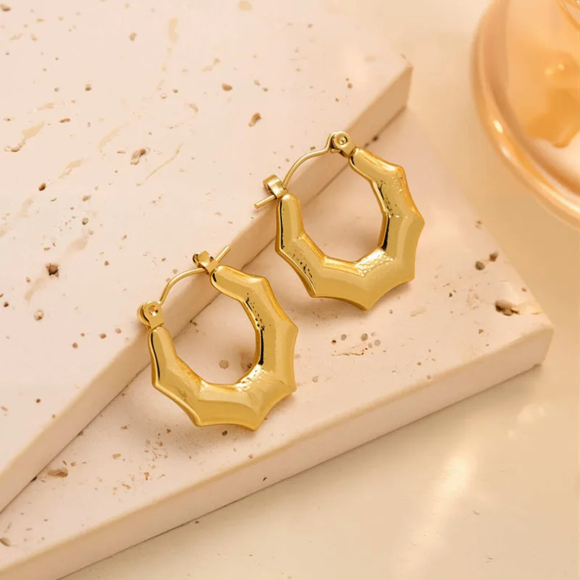 Gold hoop earrings on a textured beige surface