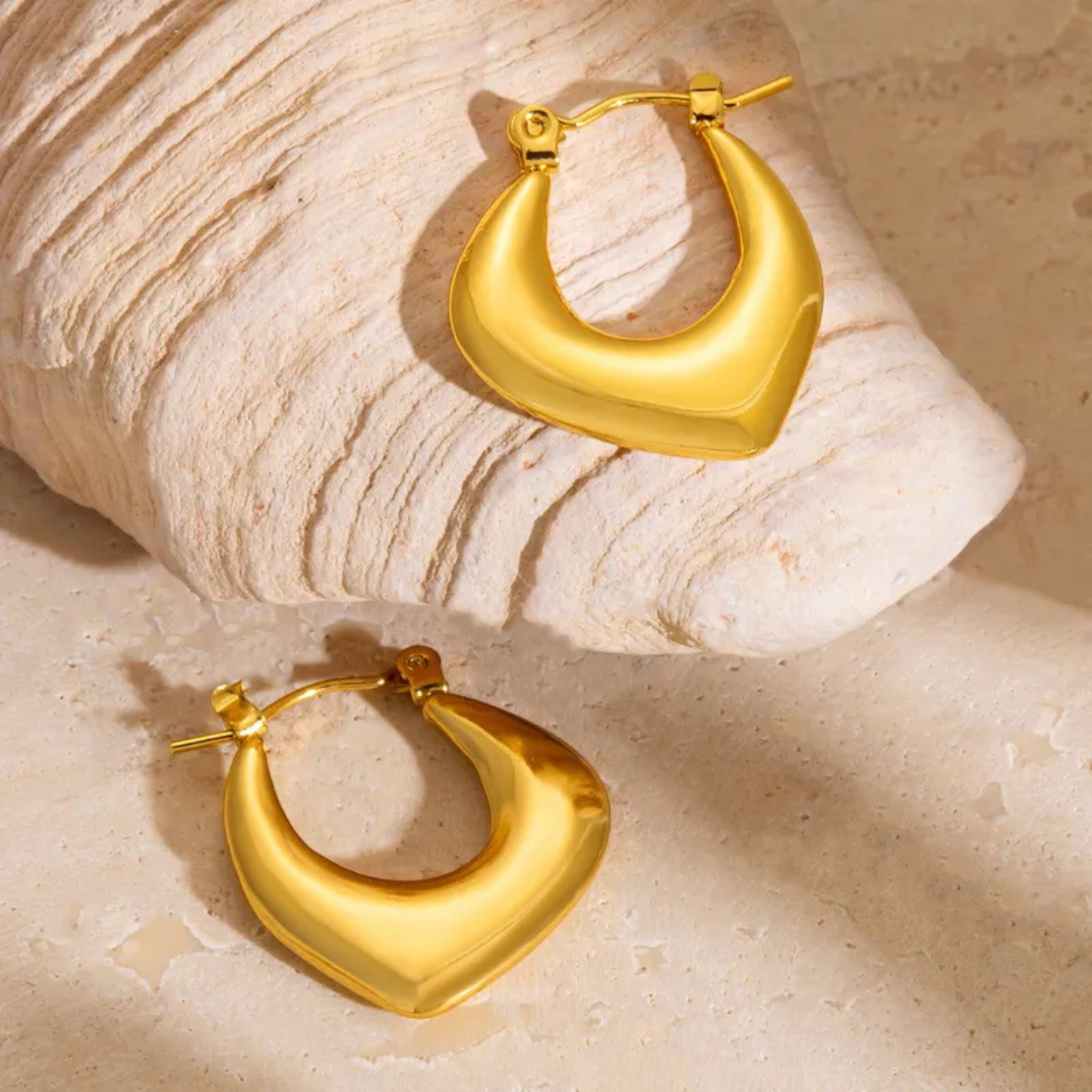 Gold hoop earrings on a textured beige surface