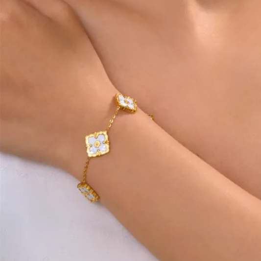 Gold bracelet with floral designs on a wrist against a neutral background