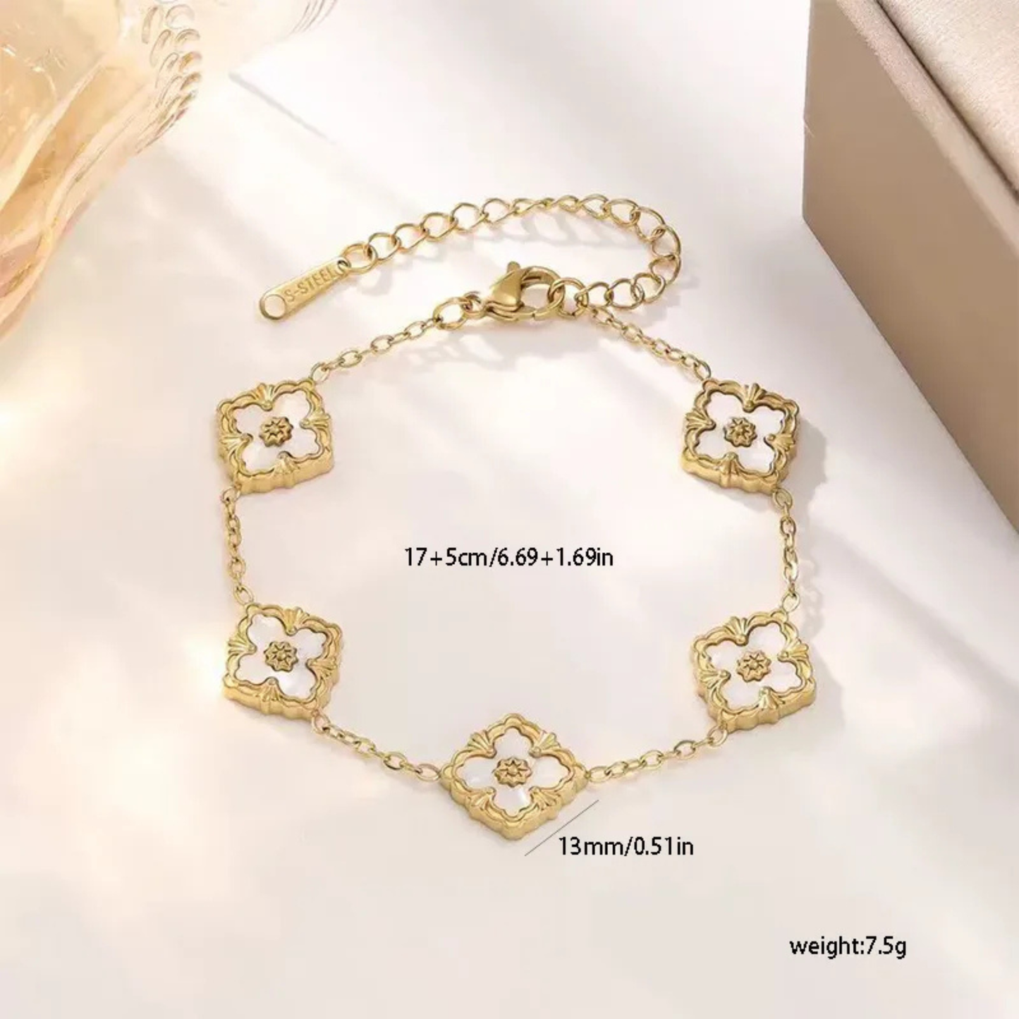 Gold bracelet with floral designs on a white surface