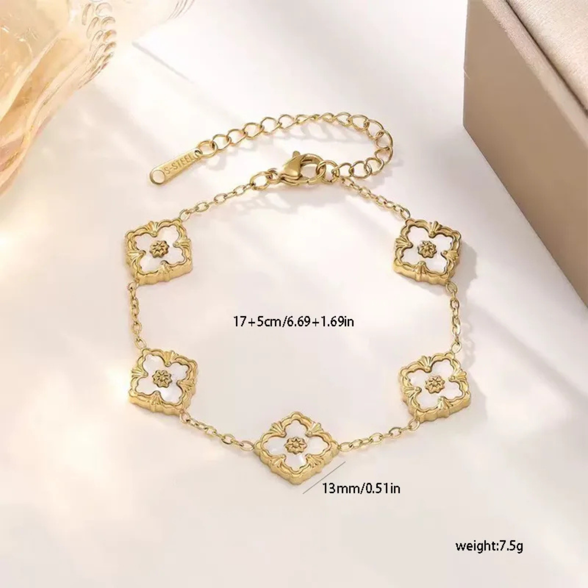 Gold bracelet with floral designs on a white surface