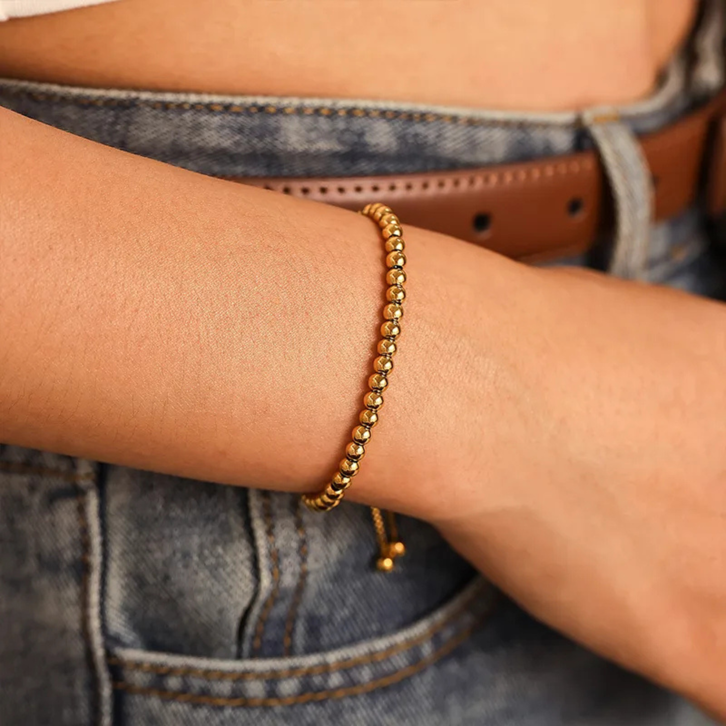 Gold bracelet on a wrist with a denim background