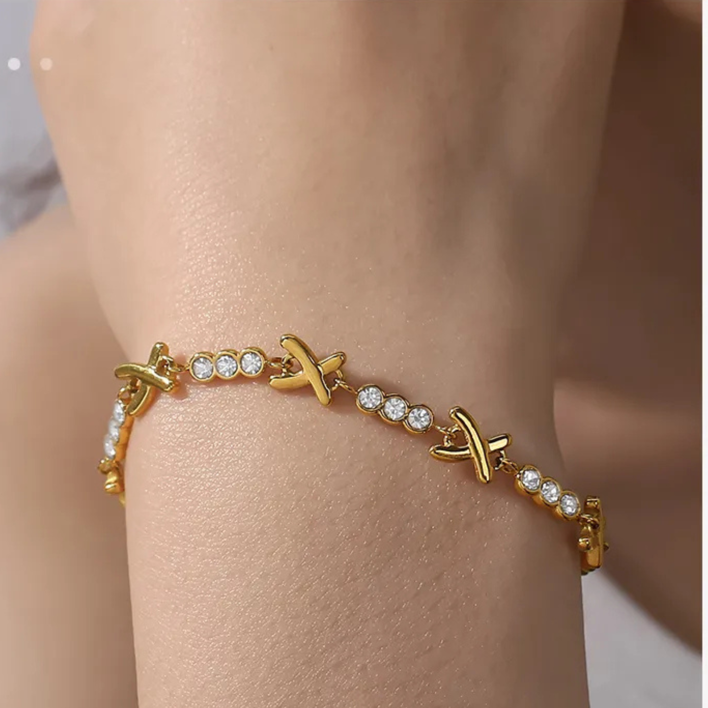 Gold bracelet with diamond accents on a wrist against a neutral background