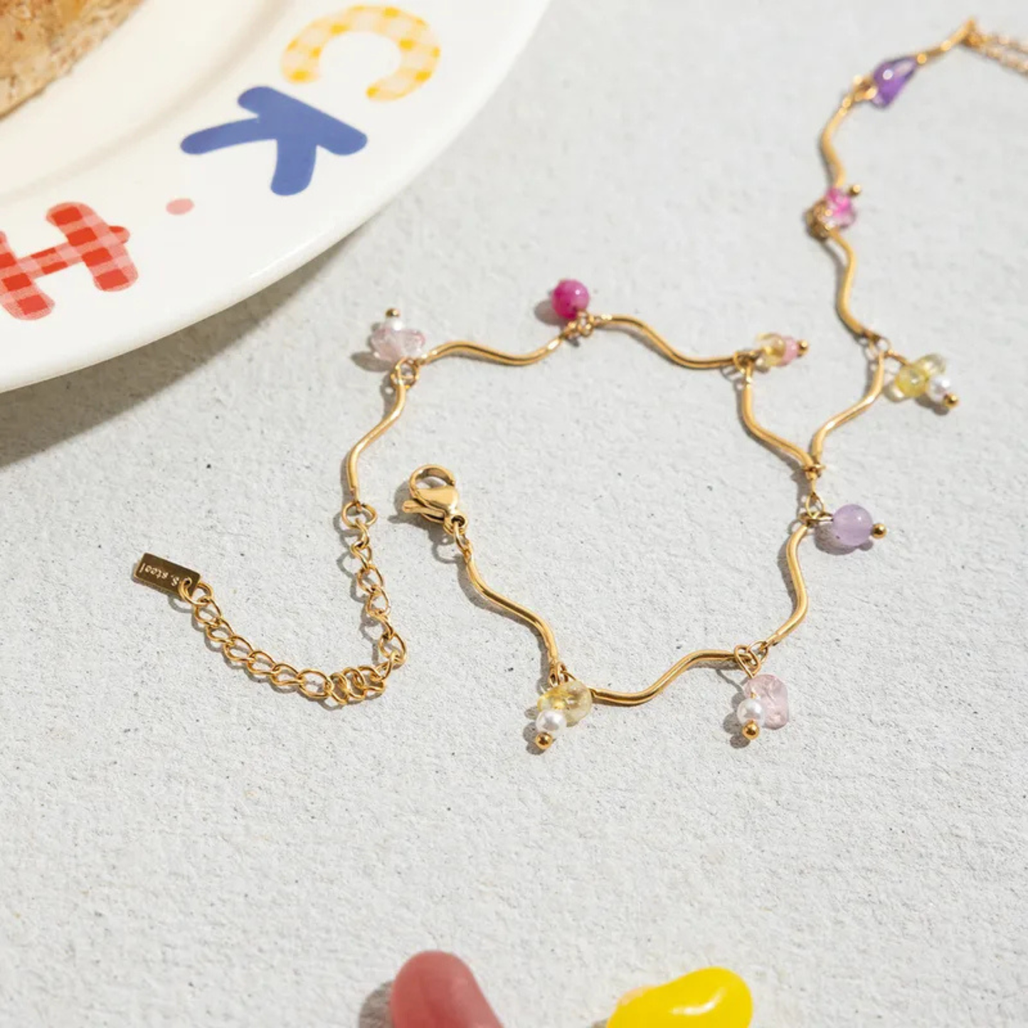 Gold bracelet with colorful beads on a textured surface