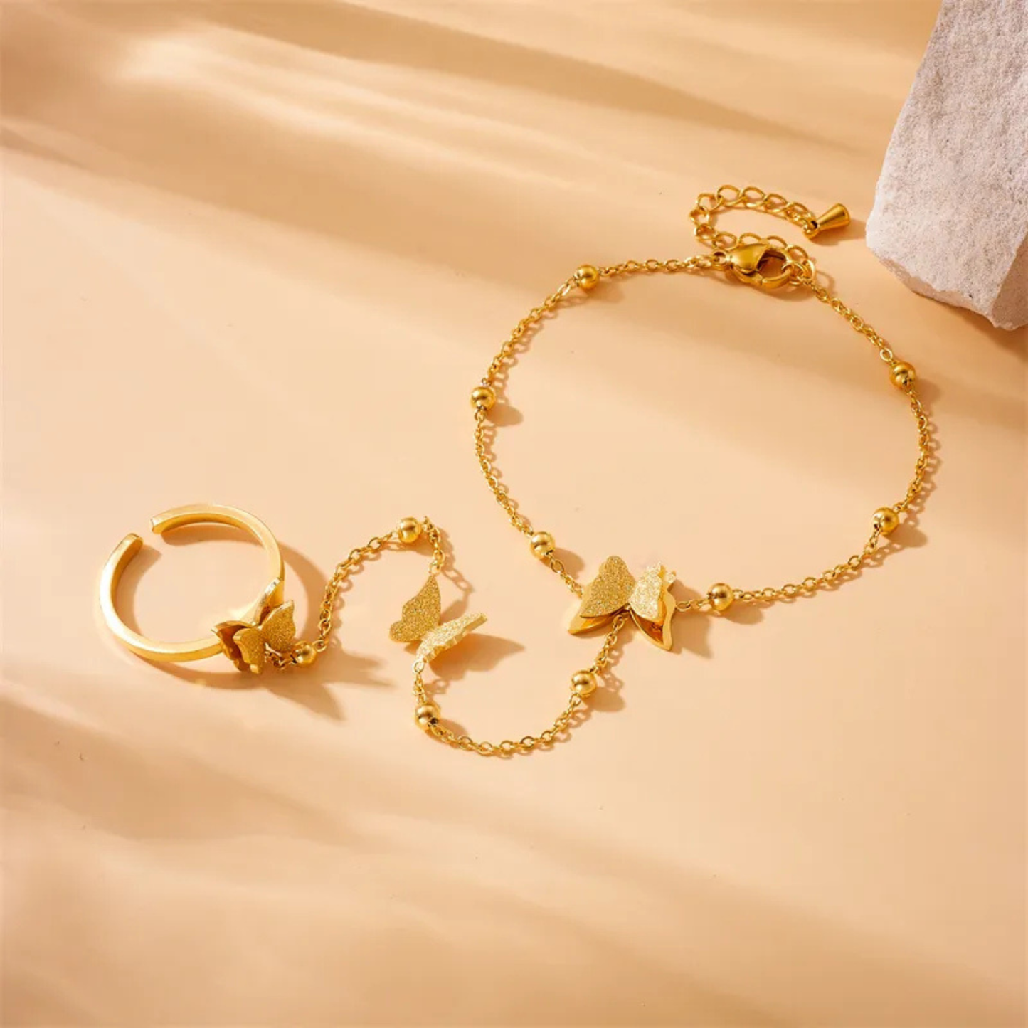 Gold bracelet and ring set on a beige background