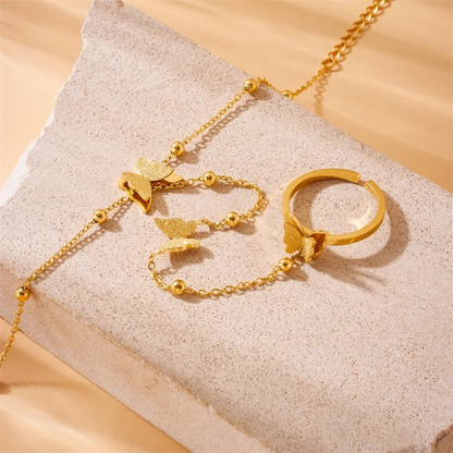 Gold jewelry set including a necklace, bracelet, and ring on a textured surface.