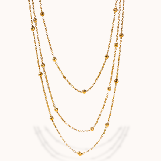 Gold chain necklace with small beads on a white background