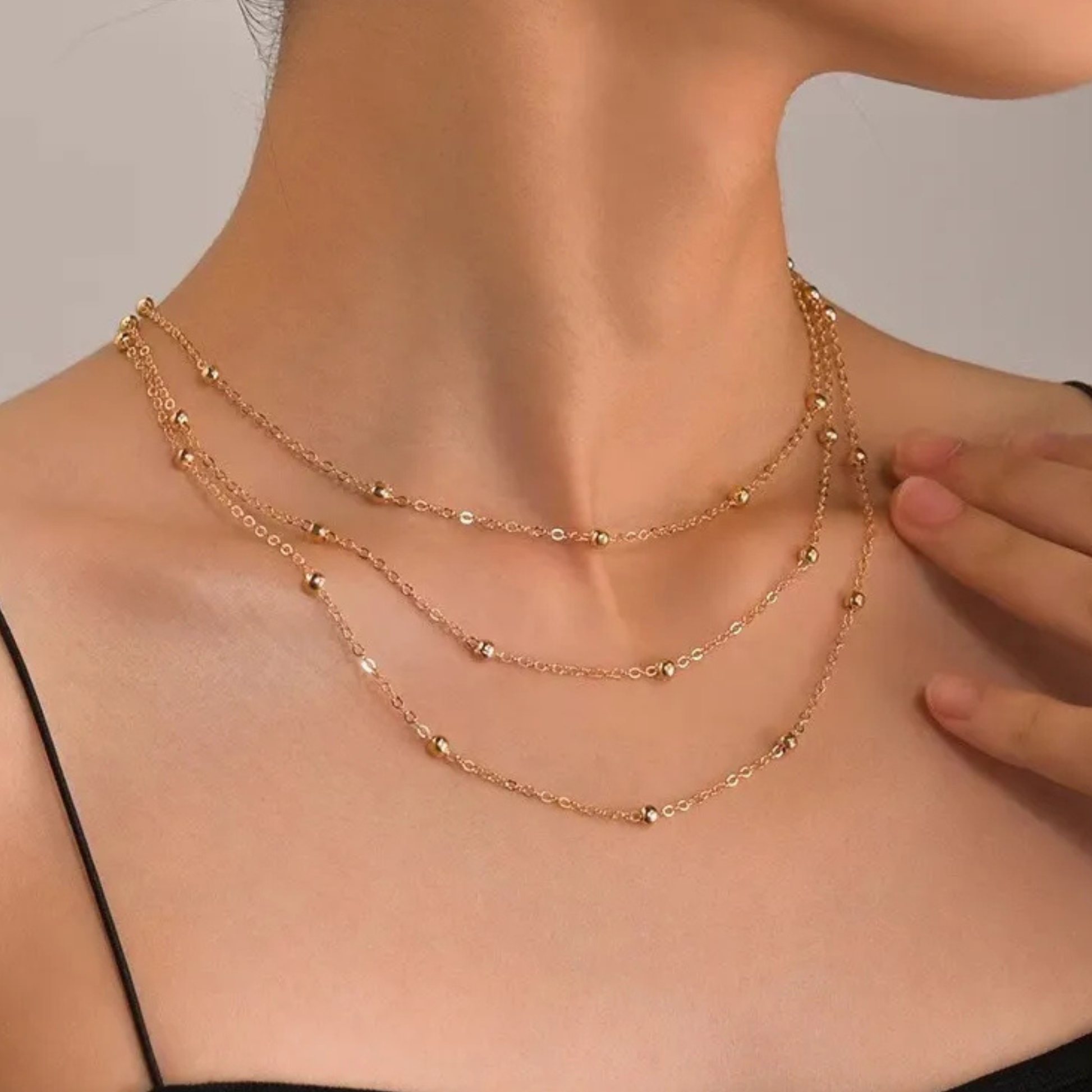 Gold necklace on a model with a neutral background