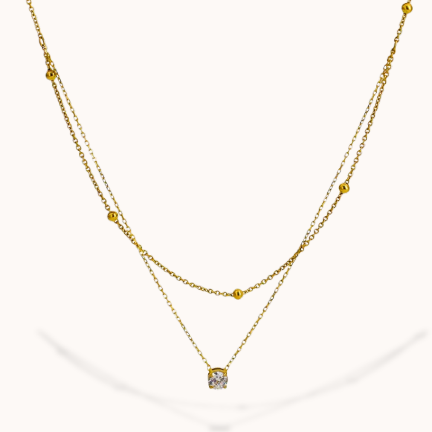 Gold necklace with a small pendant on a white background