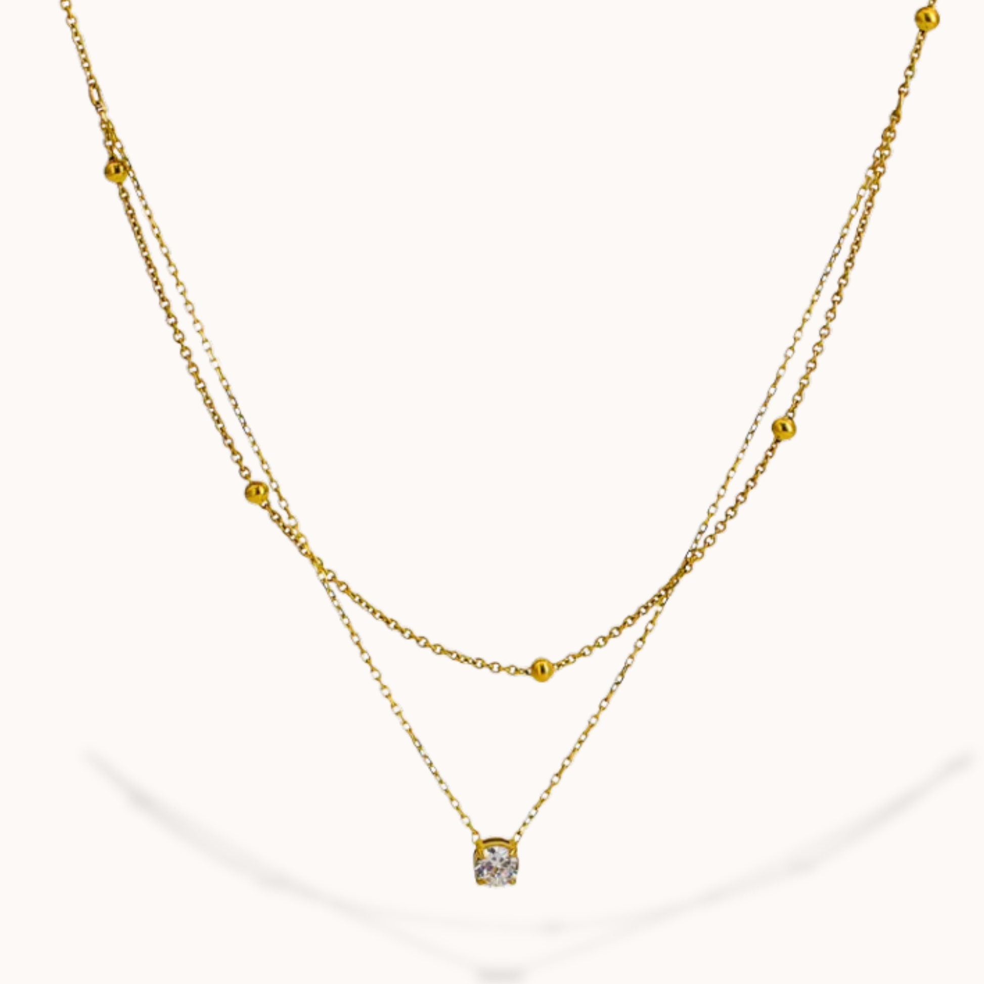 Gold necklace with a small pendant on a white background