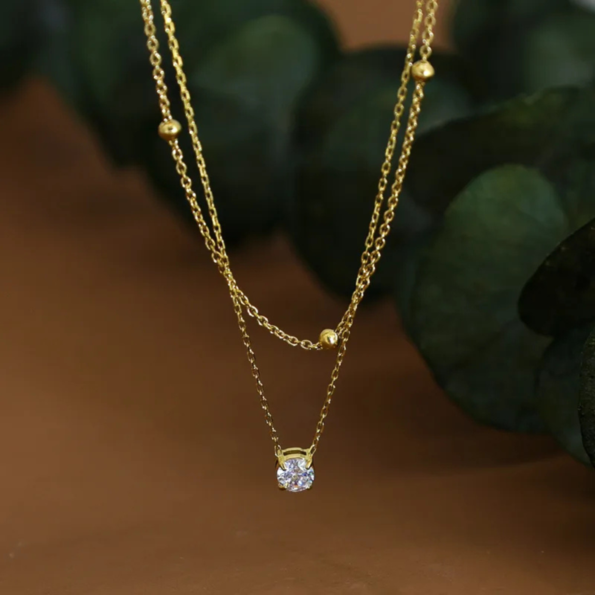Gold necklace with a diamond pendant on a brown background