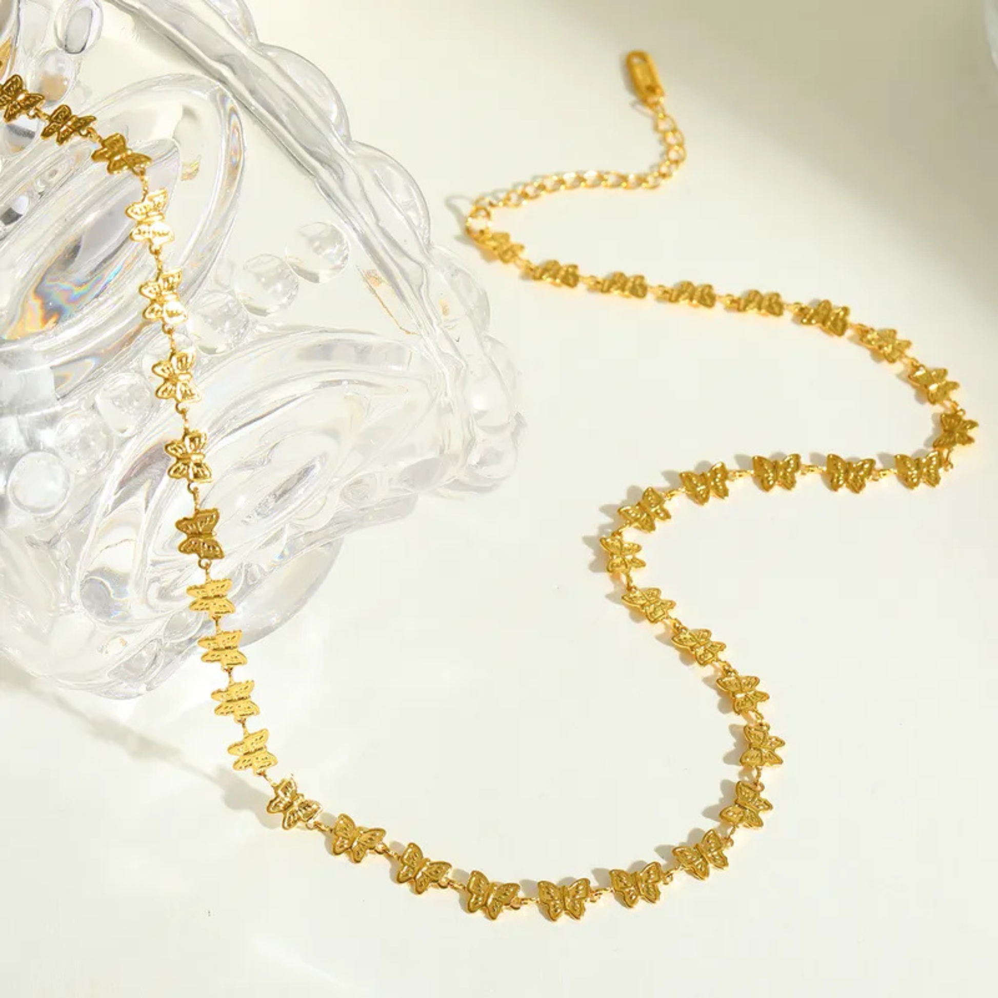 Gold necklace with butterfly designs on a white background
