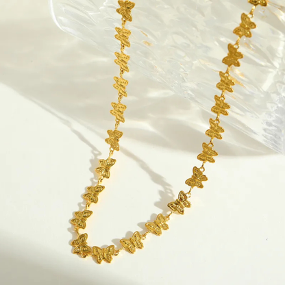 Gold butterfly necklace on a white fabric background